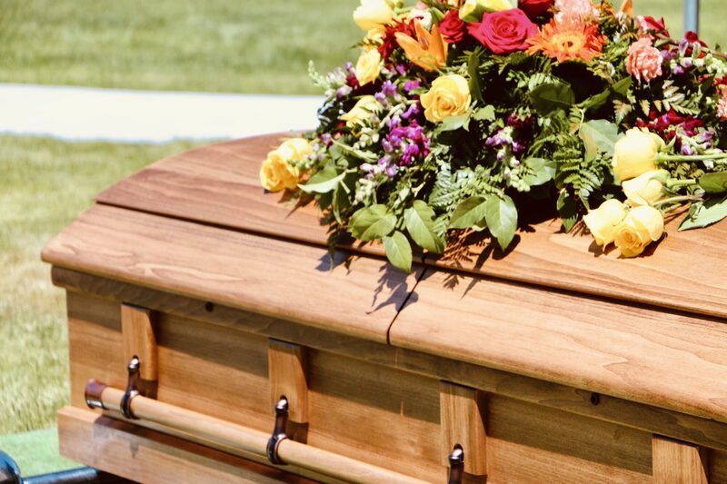 A floral casket spray in soft yellow, white and lavender blooms